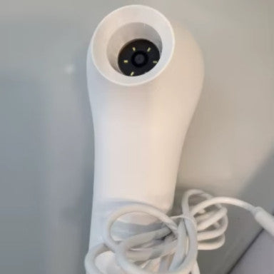 White ScalpCam scalp analysis device with cord on a light gray background, designed for at-home scalp inspection, dandruff detection, and hair root monitoring.