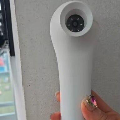 White ScalpCam handheld scalp camera by a person with pink nail polish against a white background for at-home scalp checks and dandruff detection.